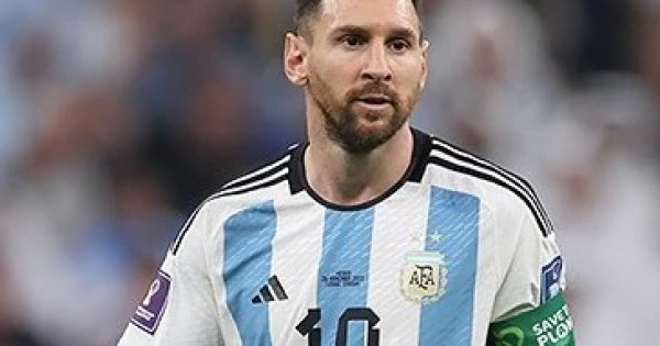 Soccer player dribbling past defenders on green pitch.